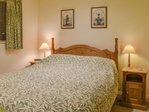 a bedroom with a bed and two lamps on tables at Honeysuckle Cottage in North Mundham