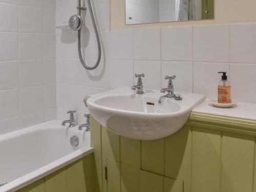 a bathroom with a sink and a bath tub at Honeysuckle Cottage in North Mundham