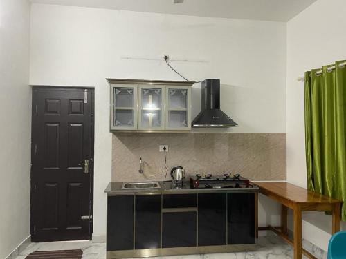 cocina con fregadero y puerta negra en Jayuz Homestay & Foodies, en Kozhikode