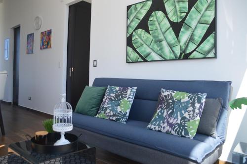 a blue couch in a living room with a painting at Cozy Stays Cayala Apartments 602 in Guatemala