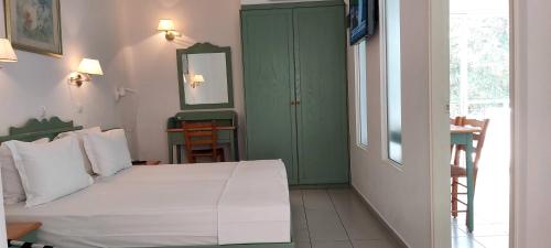 a bedroom with a white bed and a green door at Andromeda Hotel Apartments in Kos Town