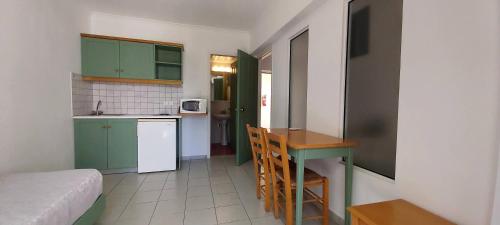a small kitchen with green cabinets and a table at Andromeda Hotel Apartments in Kos Town