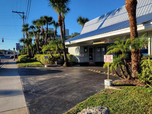 a parking lot in front of a building with palm trees at Budget Inn Winter Haven Auburndale in Winter Haven