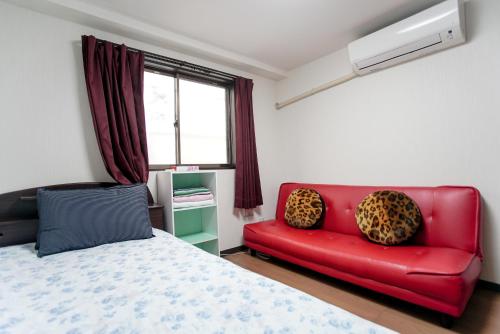 a bedroom with a red couch and a bed at Mochida's Guest House in Tokyo