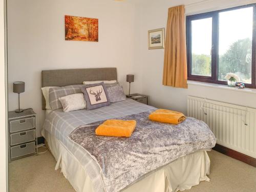 米勒姆的住宿－Combe Cairn，一间卧室配有一张带两个橙色毛巾的床