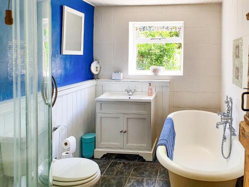 a bathroom with a tub and a toilet and a sink at Porthkerry in Oxhill
