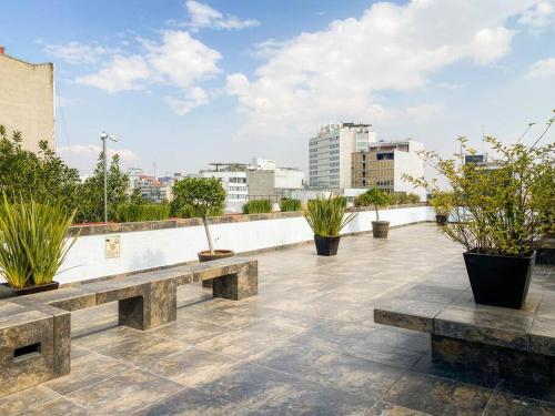 a patio with benches and potted plants on a roof at Departamento en la Condesa Roma Ciudad de México in Mexico City