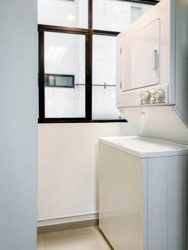 a kitchen with a white refrigerator and a window at Departamento en la Condesa Roma Ciudad de México in Mexico City
