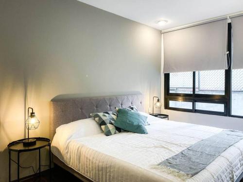 a bedroom with a bed with two pillows and a window at Departamento en la Condesa Roma Ciudad de México in Mexico City