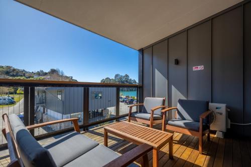 a balcony with two chairs and a table and a view at Kaiteriteri Reserve Apartments in Kaiteriteri