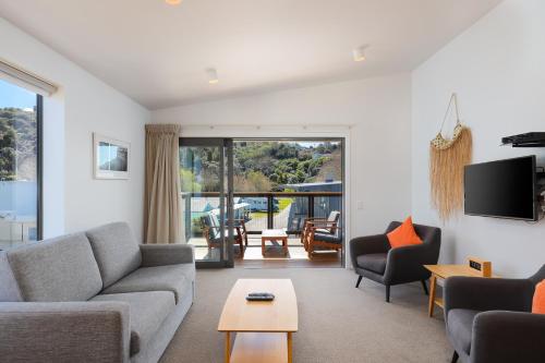 a living room with a couch and chairs and a tv at Kaiteriteri Reserve Apartments in Kaiteriteri