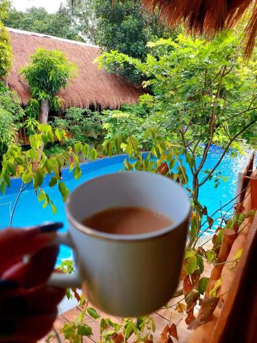 a cup of coffee sitting on a table next to a window at Habarana Tree house Mutu village in Habarana
