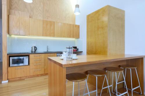 a kitchen with wooden cabinets and a bar with stools at Kaiteriteri Reserve Apartments in Kaiteriteri