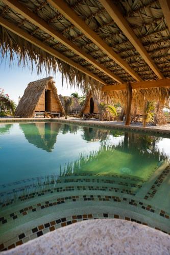 una piscina en un complejo con techo de paja en Nattivo Ecoglamping en La Sabrosa
