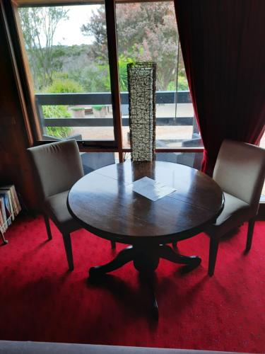 1 mesa y 2 sillas en una habitación con ventana en The Beach Cabin en Fingal