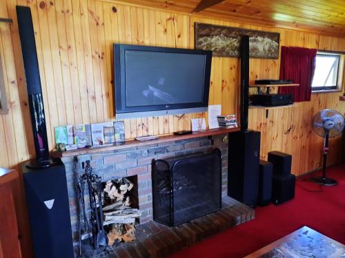 a living room with a fireplace with a flat screen tv at The Beach Cabin in Fingal