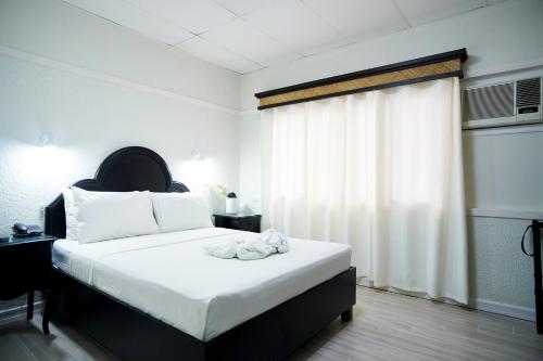 a bedroom with a bed with white sheets and a window at Dao Diamond Hotel & Restaurant in Tagbilaran City