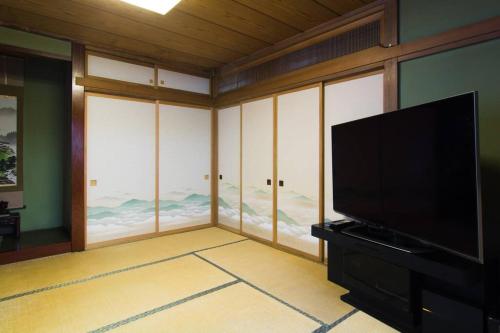 a living room with a flat screen tv and large windows at Mochida's Guest House in Tokyo