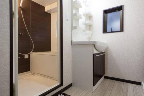 ein Bad mit einer Dusche, einem Waschbecken und einem Spiegel in der Unterkunft Mochida's Guest House in Tokio