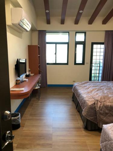 um quarto de hotel com uma cama e uma secretária com um computador em Lohas Seaview B&B em Beigan