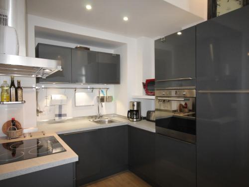 - une cuisine avec des placards gris foncé et un évier dans l'établissement Magnifique T2 avec Wifi en centre, 1 chambre, 3 étoiles - FR-1-608-85, à Le Mont-Dore