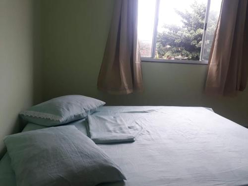 łóżko z 2 poduszkami w pokoju z oknem w obiekcie HOSPEDAGEM DA ROSE 3 w mieście Marataízes