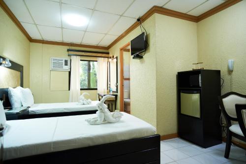 a hotel room with two beds and a tv at Dao Diamond Hotel & Restaurant in Tagbilaran City