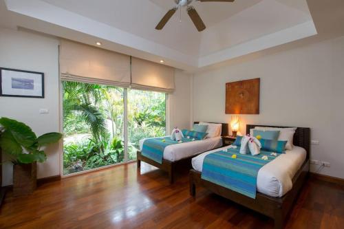 ein Schlafzimmer mit zwei Betten und einem großen Fenster in der Unterkunft Katamanda villa Moon 3 Bed seaview near Kata Beach in Kata Beach