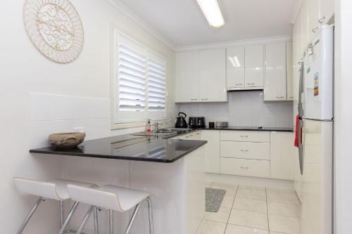 a white kitchen with white cabinets and a refrigerator at 3 of 29 Parkes St in Tuncurry