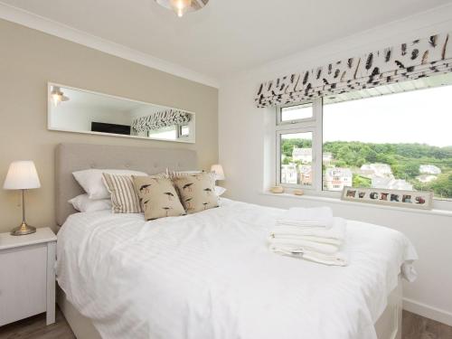 a white bedroom with a large white bed and a window at Rockmount 1 in Salcombe