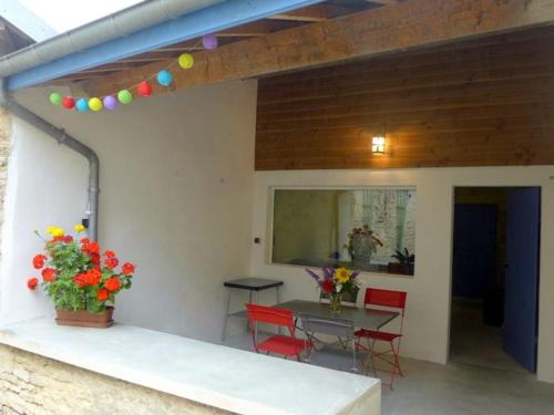 une terrasse avec une table, des chaises rouges et une table dans l'établissement Charmant Gîte au Cœur de Châteauvillain avec Terrasse et Balades en Forêt - FR-1-611-10, à Châteauvillain
