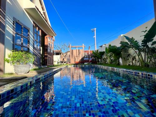 a swimming pool in front of a building with blue tiles at NGÀI Villa in Phu Yen