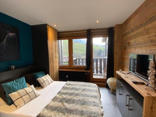 une chambre avec un lit aux murs bleus et une fenêtre dans l'établissement T2 avec Coin Nuit, Sud, Vue Montagnes, Wi-Fi, Non-Fumeur - FR-1-437-99, à La Clusaz