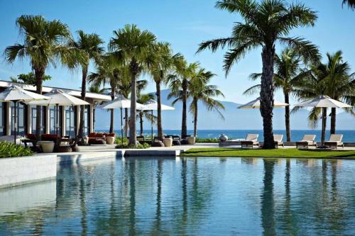 a pool at a resort with palm trees and the ocean at Villa seaview and apartment -Spa Da Nang Resort by JT group "Free pick up" in Da Nang