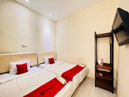 two beds in a small room with a television at RedDoorz near Alun Alun Sidoarjo in Sidoarjo