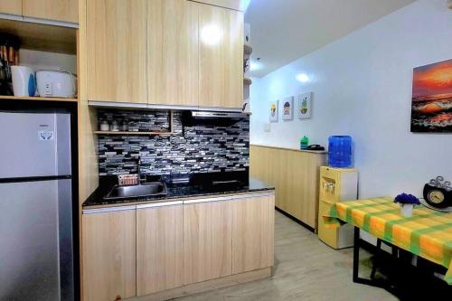 a kitchen with a sink and a refrigerator and a table at Cozy Studio Condo in San Jose del Monte in San Jose del Monte