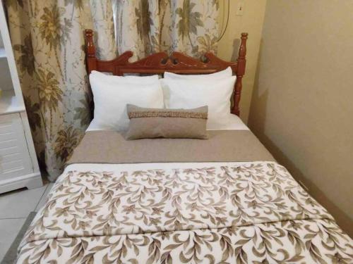 a bed with a brown and white comforter and pillows at Beach House In Crown Point- walk to the beach in Bon Accord