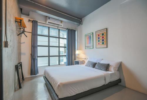 Un dormitorio con una cama y una ventana grande. en Jai Loy Cafe & Rooftop, en Chiang Mai