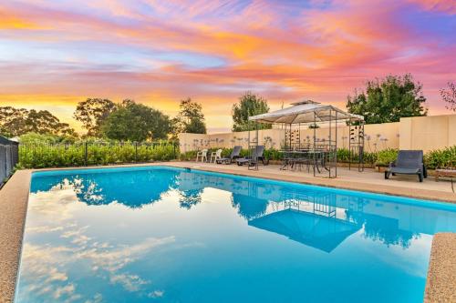 a swimming pool with a sunset in the background at Burringa Garden Motel in Wagga Wagga