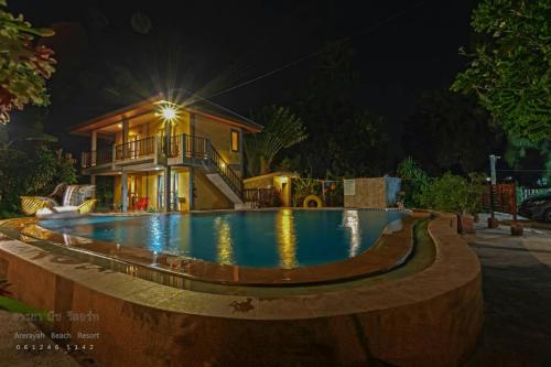 a swimming pool in front of a house at night at บ้านพักปราณบุรี อารยา บีช รีสอร์ท in Ban Nong Sua