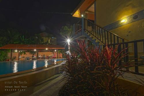 a resort swimming pool at night with a hotel at บ้านพักปราณบุรี อารยา บีช รีสอร์ท in Ban Nong Sua