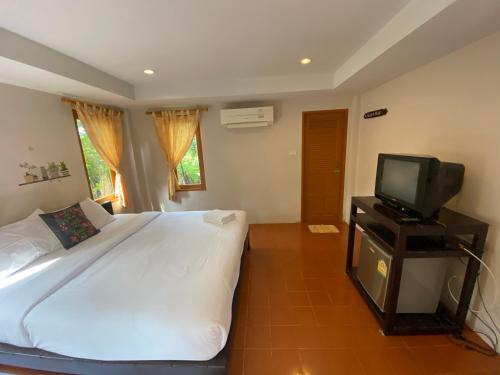 a bedroom with a large bed and a television at บ้านพักปราณบุรี อารยา บีช รีสอร์ท in Ban Nong Sua