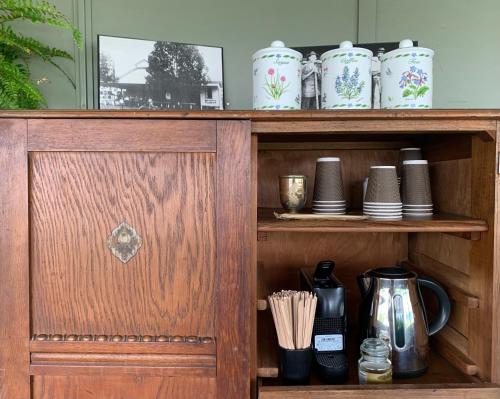 a wooden cabinet with cups and utensils on it at Tyalgum Hotel in Tyalgum