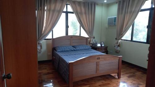 a bedroom with a bed in a room with windows at Tagaytay Rest House in Tagaytay