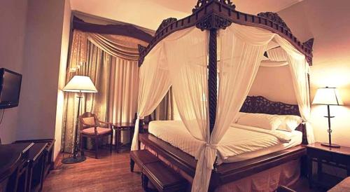 1 dormitorio con cama con dosel y sábanas blancas en Hotel Salcedo De Vigan, en Vigan
