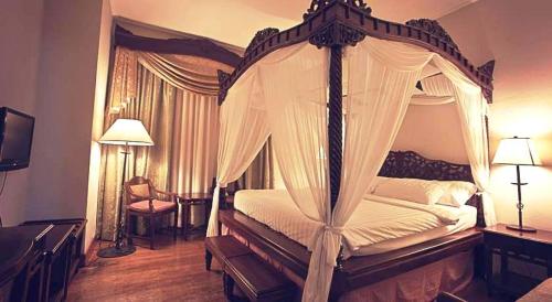 a bedroom with a canopy bed with white sheets at Hotel Salcedo De Vigan in Vigan