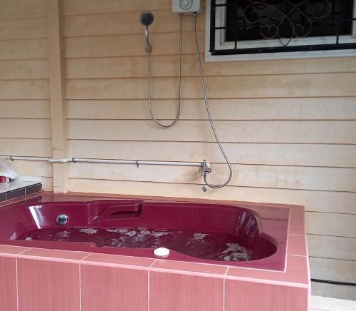 a red bath tub with a hose hooked up to a wall at Tagaytay Rest House in Tagaytay