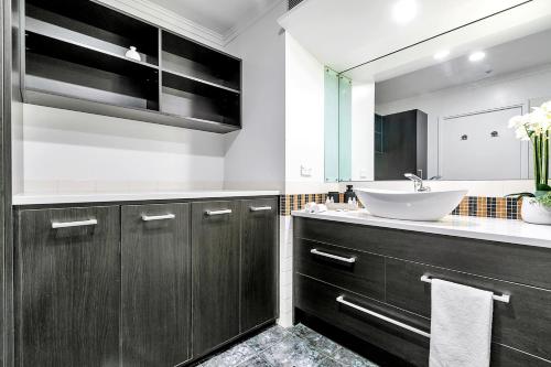 een badkamer met een wastafel en een spiegel bij The Corporate's Selection + CP! in Auckland