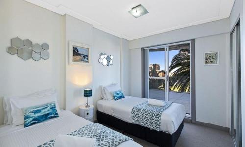 a bedroom with two beds and a window with a view at Sandy Cove Apartment The Entrance 12 in The Entrance