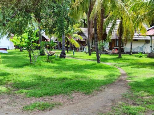 a path through a green yard with palm trees at Abdi Fantastik in Gili Air